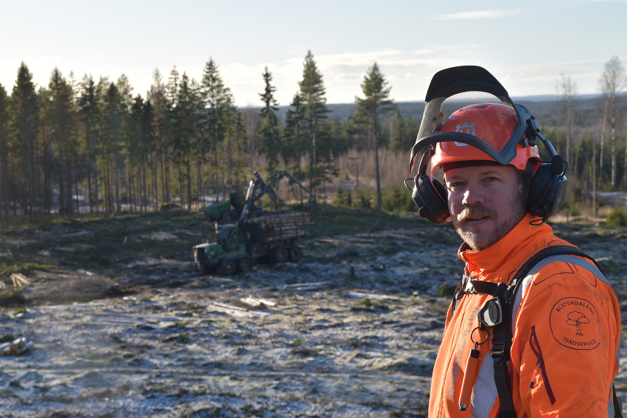 Niklas Bos i skyddsutrustning framför en skotare på ett avverkat hygge